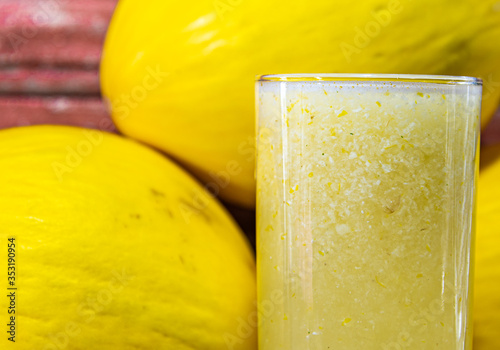 Fotografía Spanish melon juice (Cucumis mello) and fruits on aged red wooden background