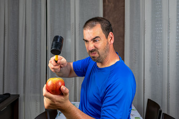 Bearded man with short hair in blue t-shirt holding an apple