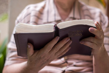 Detail from a bible carried by an elderly woman, who is reading while sitting in her garden