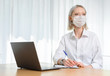 © Streetstylephoto - A young girl works with a laptop at home or in the office. antiviral mask.