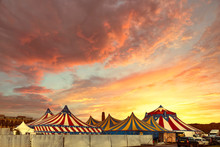 Red And White Circus Tents Topped With Bleu Starred Cover Against A Sunny Blue Sky With Clouds