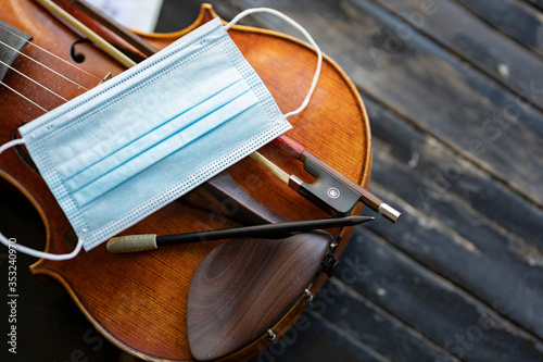 Fotografía A face mask on an acoustic violin or viola with a pencil and a bow next to it re