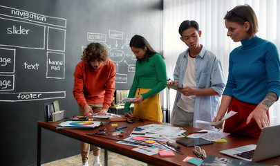 Wall Mural - great colors for our website. group of four web designers in casual wear developing new web site lay