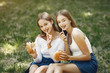 © hetmanstock2 - Beautiful girls in a jeans skirts. Women in a summer park. Friends with a burgers