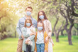 © travnikovstudio - Adorable family in blooming cherry garden in masks