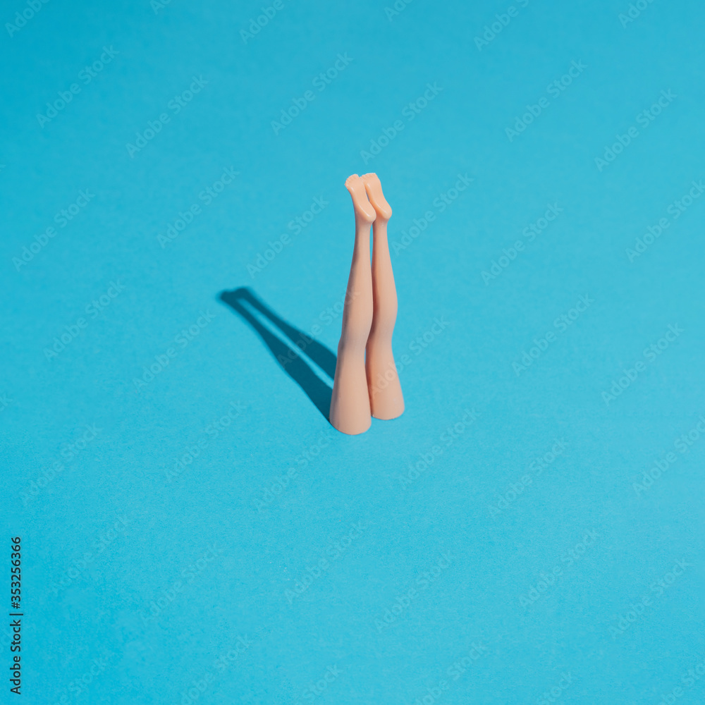 Minimal composition with doll legs and blue background. Sun and sharp shadows. Summer pool or sea diving concept. Vacation and relax inspiration. - obrazy, fototapety, plakaty 