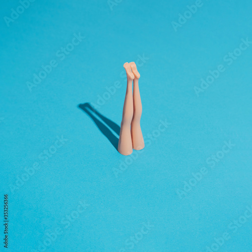 Fotografía Minimal composition with doll legs and blue background