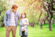 © travnikovstudio - Family of father and daughter in blooming cherry garden in masks