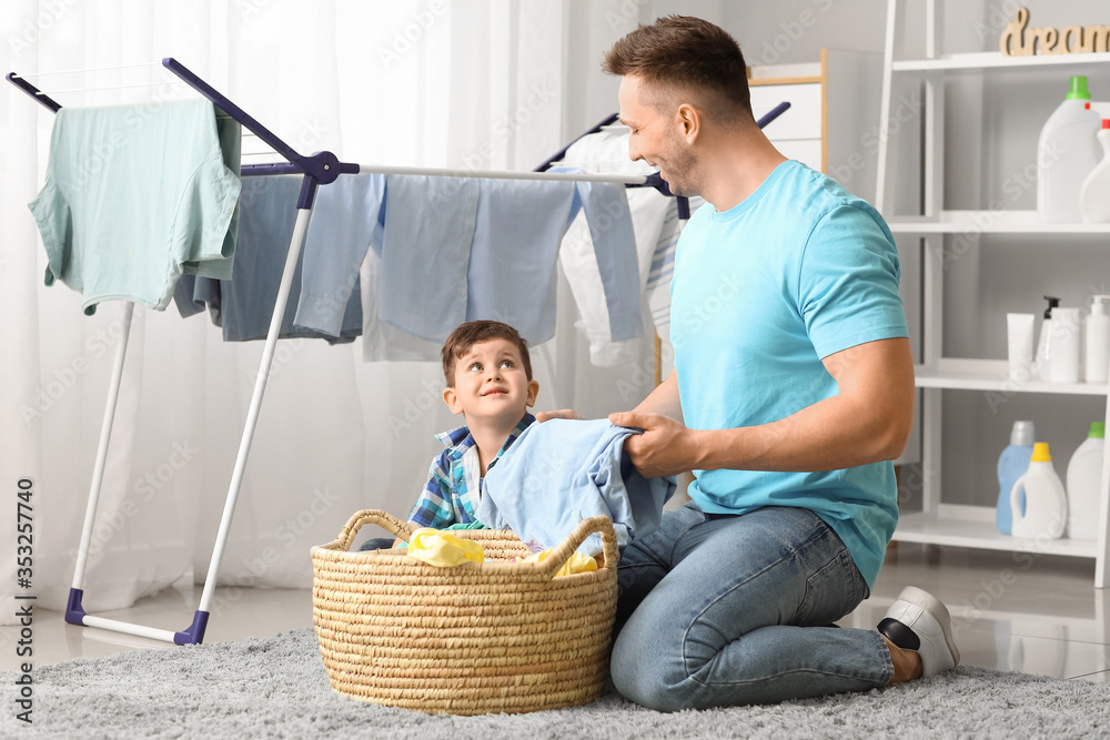 Man and his little son doing laundry at home