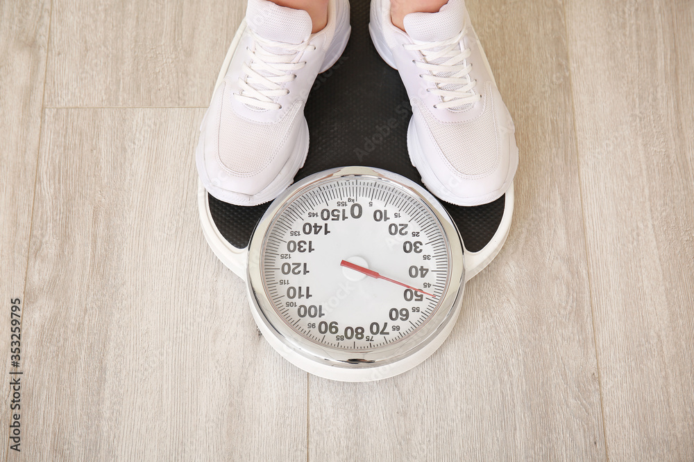 Young woman measuring her weight at home, closeup