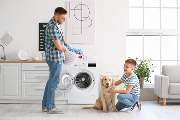 Man and his little son with cute dog doing laundry at home