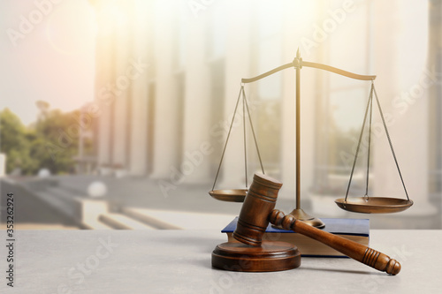 Fotografía Wooden gavel, scales of justice and book on table against beautiful cityscape, s