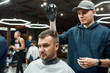 © Svitlana - Hair styling. Handsome bearded man sitting in armchair in the barbershop while young barber styling his hair with styling powder. Barbershop