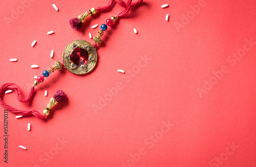 Fotografía Raksha Bandhan, Indian festival with beautiful Rakhi and Rice Grains on red background