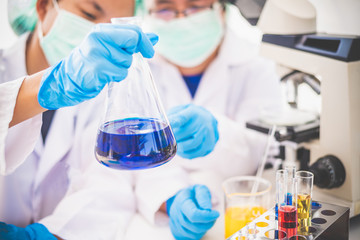 Wall Mural - Young woman researcher doing experiment equipment and science experiments oil pouring scientist with test tube yellow making research in laboratory.