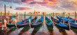 Panoramic summer view of the gondolas parked beside the Riva degli Schiavoni in Venice, Italy, Europe. Captivating mediterranean landscape wit Church of San Giorgio Maggiore on background.