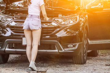 Blurred images, An Asian woman is having a problem with a car that has broken down on the way and she opens the hood to check where the car is causing damage before calling a nearby mechanic to help.