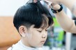 Asian boy is cut his hair in barber shop - people in hairdresser beauty salon concept