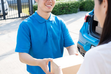 Wall Mural - Delivery service male in uniform give cardboard box package to receiver customer client front home, fast express offsite when crisis coronavirus, covid19 new normal lifestyle concept.