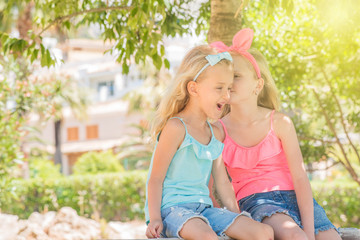 Little pretty girls having fun outdoor. Two cute girls are telling a secret. Best friends.