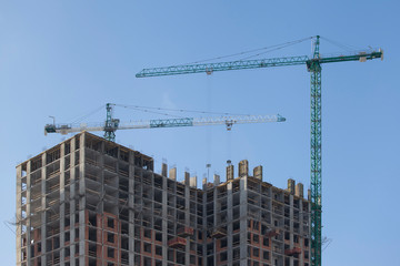 Construction site with cranes against the blue sky