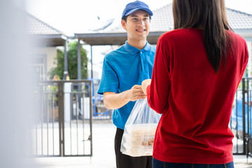 Wall Mural - Food Delivery man wearing mask handing plastic bags shopping online from supermarket to female client service customer front house, express grocery when coronavirus covid19 new normal lifestyle.