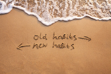 old habits vs new habits, life change concept written on sand