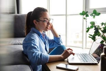 Wall Mural - Image of pleased woman working with laptop and smiling while sitting