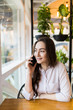 Young charming woman calling with cell telephone while sitting alone in coffee shop during free time