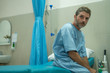© TheVisualsYouNeed - scared and worried man hospitalized - attractive injured man sitting on hospital bed receiving treatment feeling sick and unwell after suffering accident or serious disease