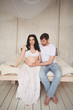 © Алина Троева - Pregnancy and people concept - happy man hugging his beautiful pregnant wife at home. Future parents waiting unborn baby. Love, relationship, birth, happy family concept - young lovely married couple