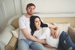 © Алина Троева - Pregnancy and people concept - happy man hugging his beautiful pregnant wife at home. Future parents waiting unborn baby. Love, relationship, birth, happy family concept - young lovely married couple