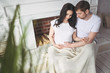 © Алина Троева - Pregnancy and people concept - happy man hugging his beautiful pregnant wife at home. Future parents waiting unborn baby. Love, relationship, birth, happy family concept - young lovely married couple