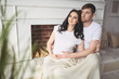 © Алина Троева - Pregnancy and people concept - happy man hugging his beautiful pregnant wife at home. Future parents waiting unborn baby. Love, relationship, birth, happy family concept - young lovely married couple