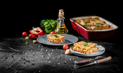 Wall Mural - Traditional italian lasagna with vegetables, minced meat and cheese On a dark background. Homemade meat lasagna