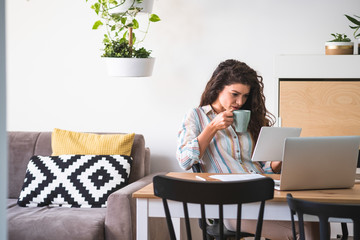 Wall Mural - Woman drinking coffee and looking at tablet stock photo