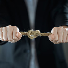 The Businessman's Hands Tighten The Rope Knot Against Background Of Suit In Blur.