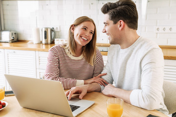 Canvas Print - Portrait of couple using laptop and talking while having breakfast