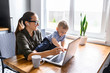 © Vadim Pastuh - Stay home. Mother works from home, she sits in the kitchen and using laptop for remote work, her cute baby boy sits on the table