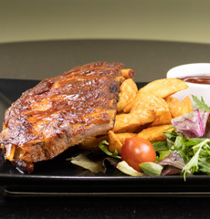 Baked pork ribs with barbecue or BBQ sauce and wedges