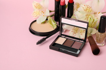 Different makeup cosmetics and flowers on pink background. Female accessories