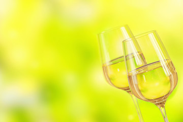 Two glasses of white wine served with cheese board on light green background. Wine mood concept