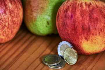 Wall Mural - Fruit lying together with European coins on a wooden background.