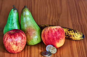 Wall Mural - Fruit lying together with European coins on a wooden background.