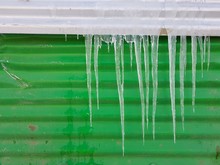 Closeup Of Icicles On A Green Facade Background
