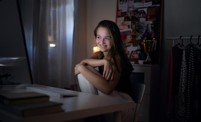 Wall Mural - Happy young girl with laptop at night smiling, online dating concept.