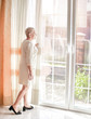 © Flena_13 - A happy, elegant senior woman stands by the window of her room.