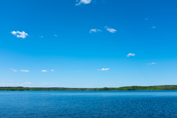 Poster - beautiful lake with sky and clouds with forest on the horizon