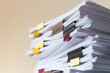 © NuPenDekDee - Pile of student homework that assigned to student to be completed outside class on teacher desk separated by colored paper clips. Document stack arranged by paperclip. Business and education concept.
