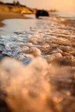 Close Up Bokeh Of The Waves Water Being Lit Up By The Warm Orange Glow Of The Sun During Sunset